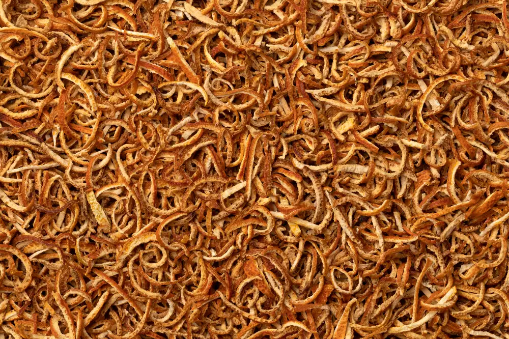 Curled dried bitter orange peel strips (Citrus aurantium) with golden-orange coloring.